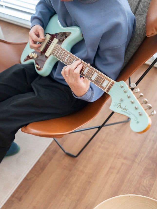 中古マンションのリノベーション後のリビングでギター演奏する男性